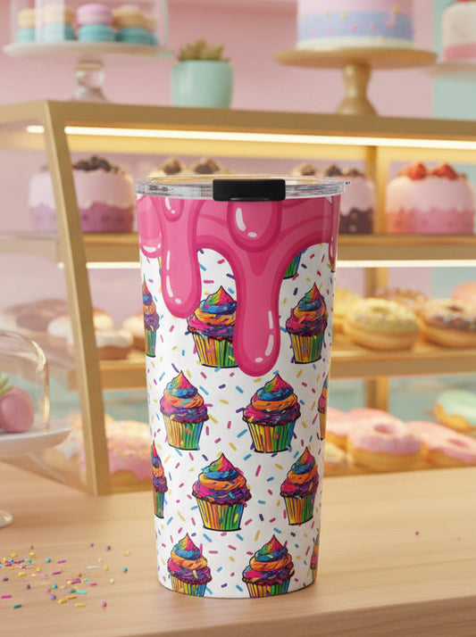 A tall insulated tumbler with a clear lid and black flip-straw, featuring a white background printed with colorful rainbow cupcakes and dripping pink frosting, shown on a light gray studio background.